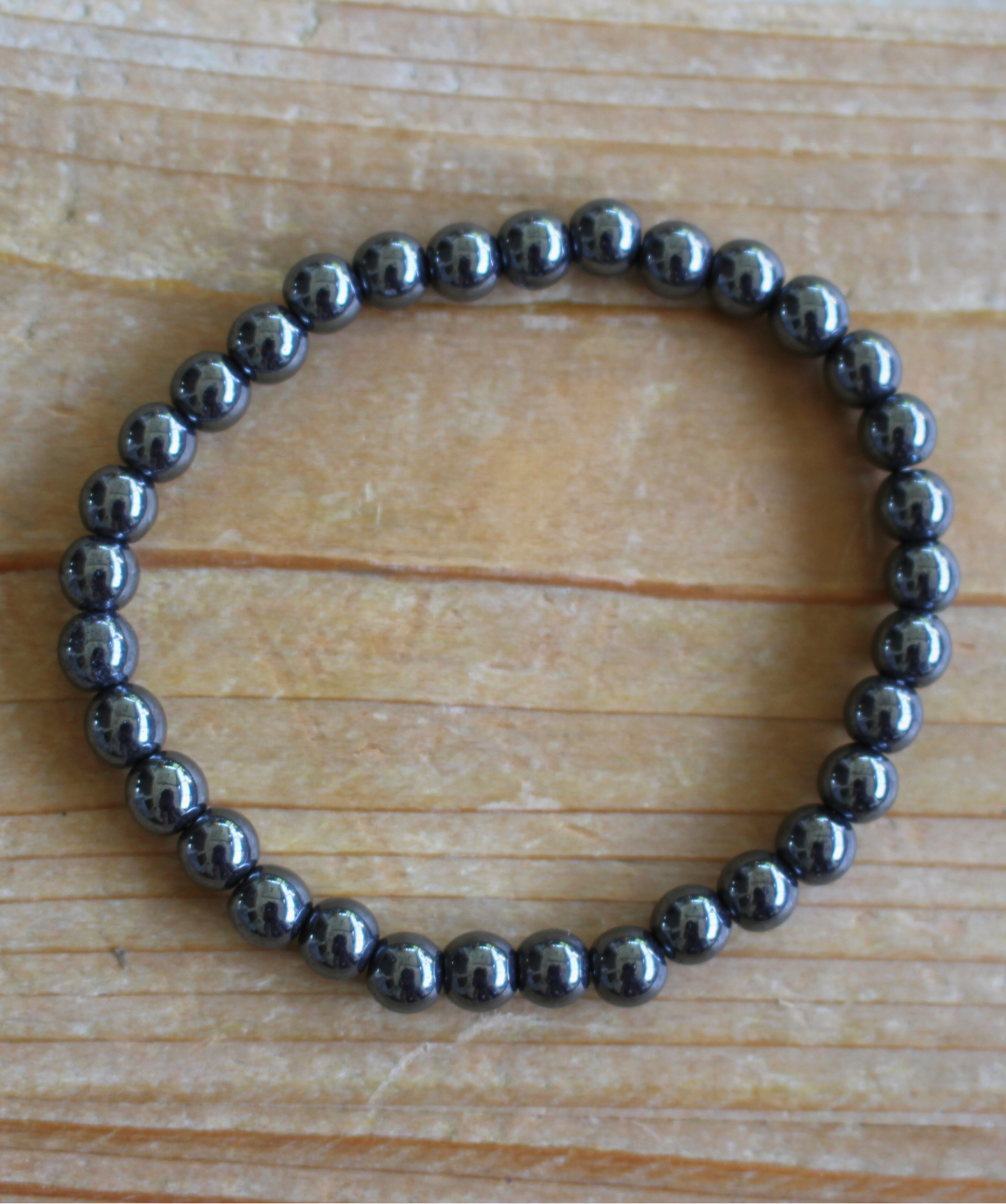 Bracelet en hématite naturelle, perles lisses de 6 mm au reflet métallique argenté. Pierre d’ancrage, de vitalité, de courage,  l’hématite aide à rester centré et à renforcer la confiance en soi. À porter sur le poignet droit, côté émetteur, pour diffuser ses énergies protectrices et dynamisantes. Idéal le matin pour renforcer la confiance en soi, l’ancrage et la vitalité.