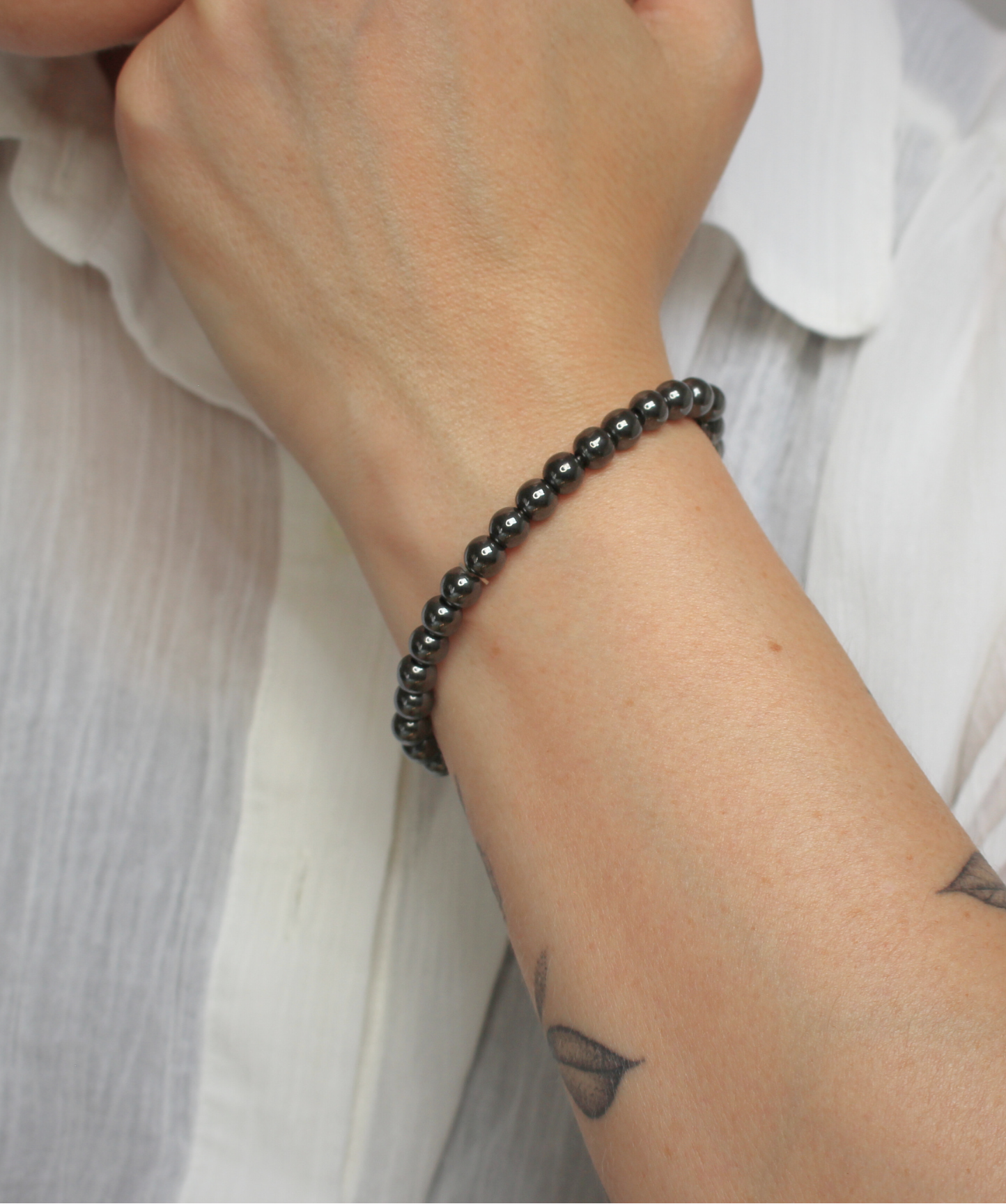 Bracelet en hématite naturelle, perles lisses de 6 mm au reflet métallique argenté. Pierre d’ancrage, de vitalité, de courage,  l’hématite aide à rester centré et à renforcer la confiance en soi. À porter sur le poignet droit, côté émetteur, pour diffuser ses énergies protectrices et dynamisantes. Idéal le matin pour renforcer la confiance en soi, l’ancrage et la vitalité.