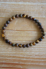 Bracelet en perles d’œil de tigre naturel 6 mm  Pierre protectrice par excellence, elle agit comme un bouclier énergétique et renforce la confiance et la volonté. À porter au poignet droit pour diffuser ses énergies protectrices et stabilisantes. À porter le matin ou pendant la journée, car il stimule le courage, la confiance en soi et la protection contre les influences négatives. L’œil de tigre aide à garder force intérieure.