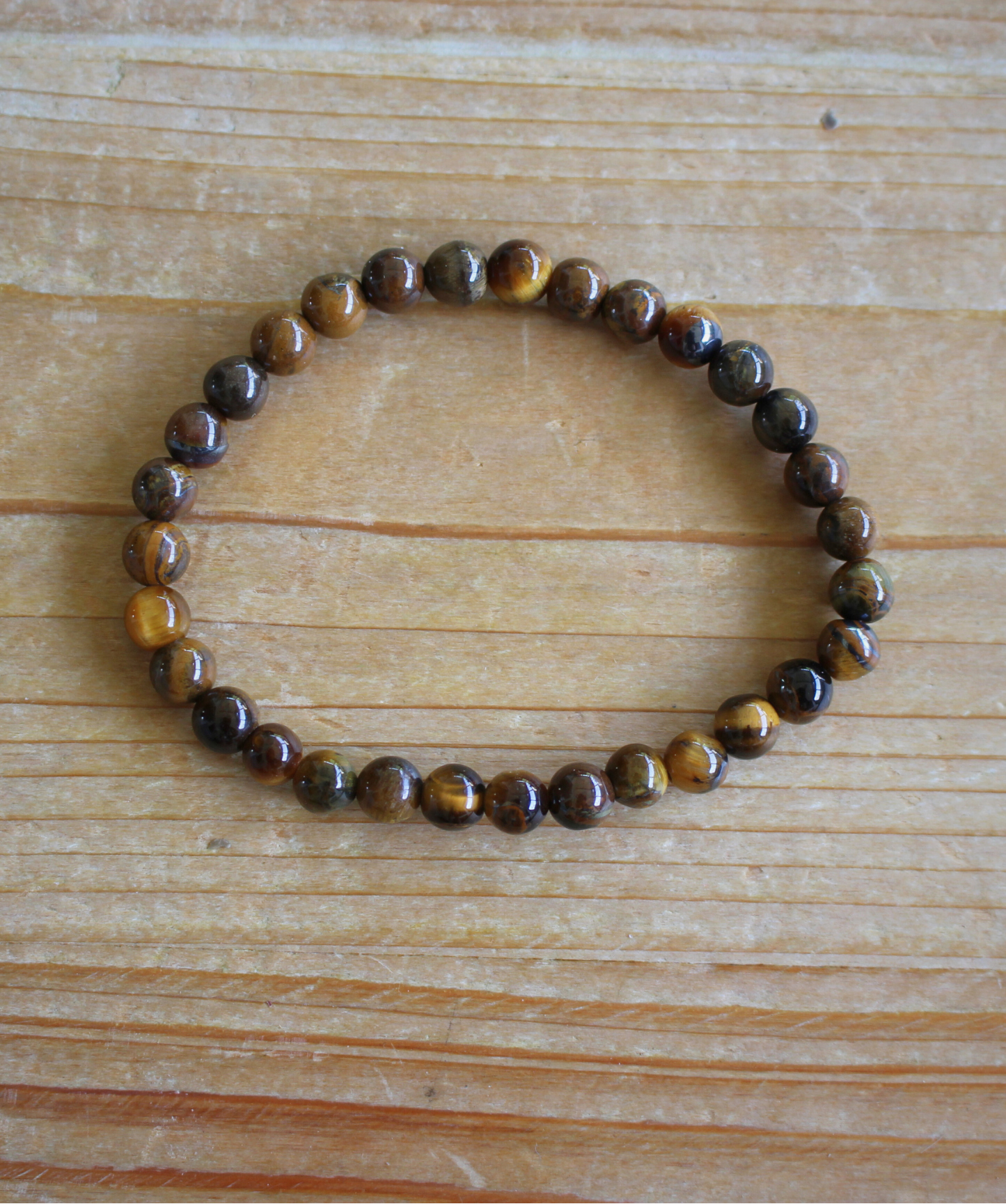 Bracelet en perles d’œil de tigre naturel 6 mm  Pierre protectrice par excellence, elle agit comme un bouclier énergétique et renforce la confiance et la volonté. À porter au poignet droit pour diffuser ses énergies protectrices et stabilisantes. À porter le matin ou pendant la journée, car il stimule le courage, la confiance en soi et la protection contre les influences négatives. L’œil de tigre aide à garder force intérieure.