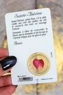 Cette carte de prière plastifiée est dédiée à Sainte Thérèse de Lisieux, aussi connue sous le nom de "la petite Thérèse" ou "la petite fleur de Jésus". Sur le recto, une image douce et inspirante de la sainte, accompagnée d’un véritable pétale de rose inséré dans une fenêtre transparente. Au verso, une prière à Sainte Thérèse, à réciter pour lui confier ses intentions et recevoir ses grâces.
