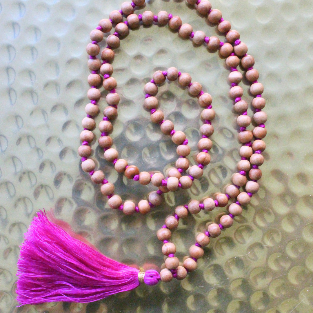 Mala 108 perles en bois de santal naturel, pompon fuchsia. Parfum boisé apaisant, idéal méditation et mantra. Porté en collier au quotidien. Artisanal, 30g.