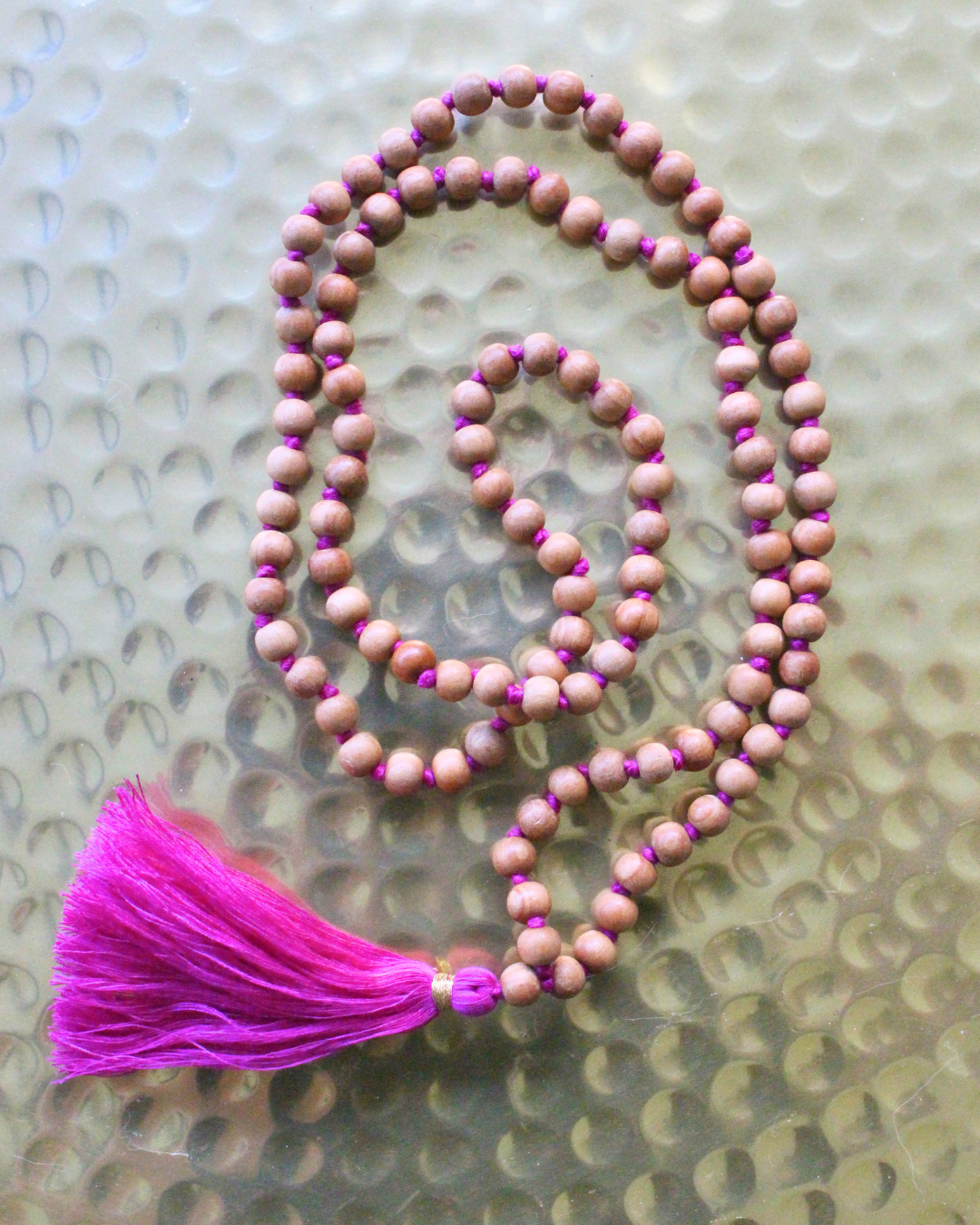 Mala 108 perles en bois de santal naturel, pompon fuchsia. Parfum boisé apaisant, idéal méditation et mantra. Porté en collier au quotidien. Artisanal, 30g.