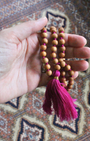 Mala 108 perles en bois de santal naturel, pompon fuchsia. Parfum boisé apaisant, idéal méditation et mantra. Porté en collier au quotidien. Artisanal, 30g.