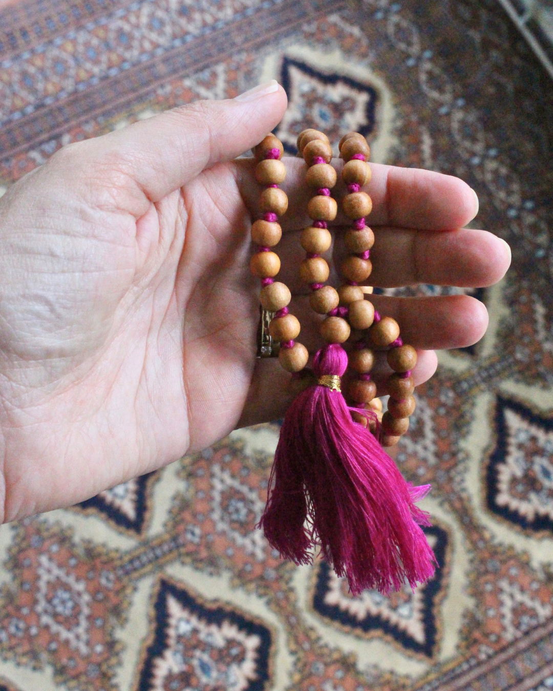 Mala 108 perles en bois de santal naturel, pompon fuchsia. Parfum boisé apaisant, idéal méditation et mantra. Porté en collier au quotidien. Artisanal, 30g.
