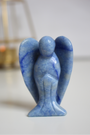 Sculpté à la main dans une aventurine bleue naturelle du Brésil, cet ange de 5 cm incarne la douceur, la sérénité et la communication bienveillante. Sa couleur bleue apaisante en fait une pièce décorative autant qu’un support énergétique puissant. Il est idéal pour favoriser l’expression, apaiser le stress et prendre du recul. 