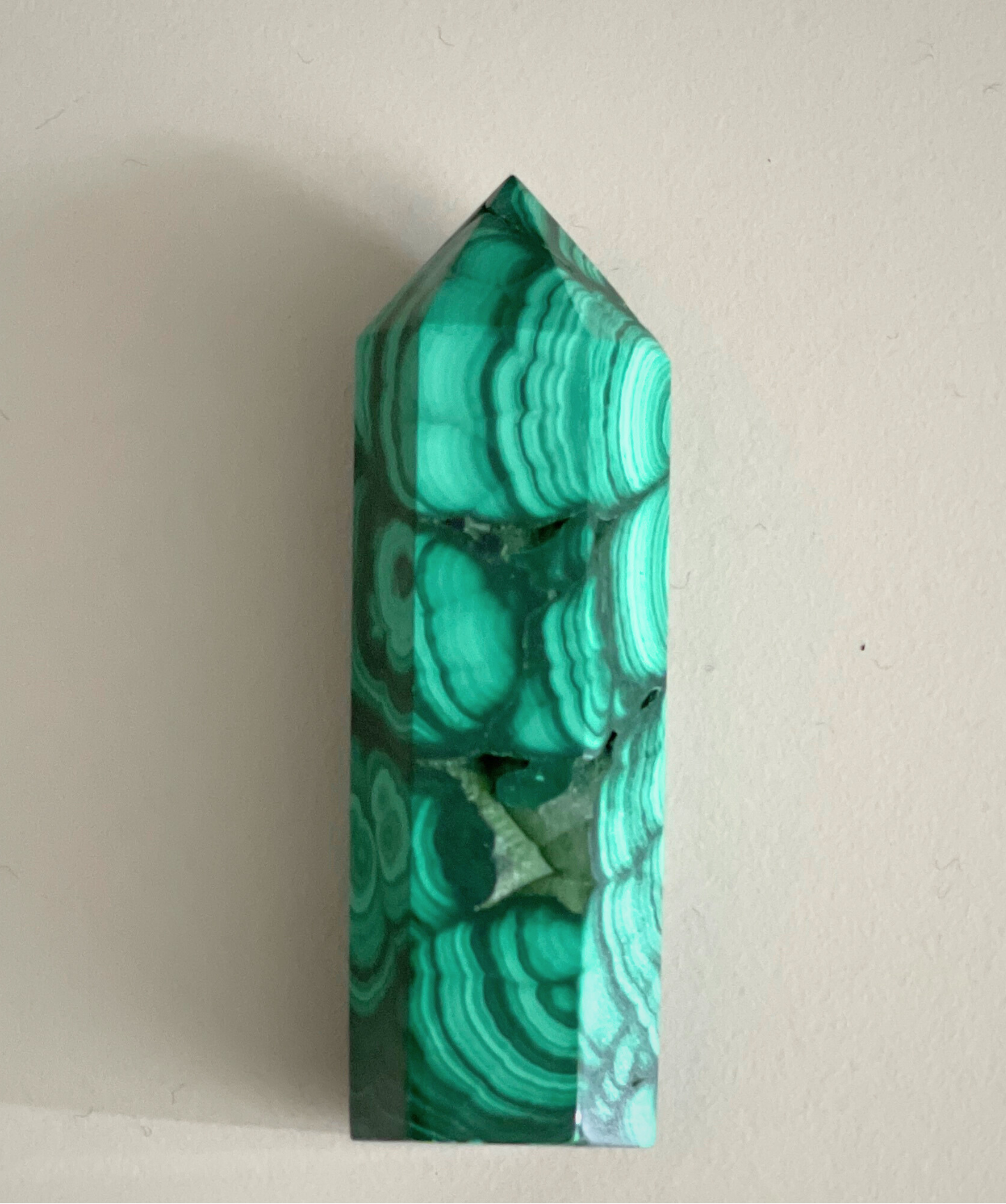 Jolie pointe en malachite naturelle polie extraite au Congo. La malachite est idéale pour être posée sur un autel, utilisée en méditation, ou placée dans un espace de soin pour favoriser le réalignement énergétique. La malachite est une pierre puissante liée au chakra du coeur, connue pour sa capacité à absorber les énergies négatives et à accompagner les grandes transformations personnelles.