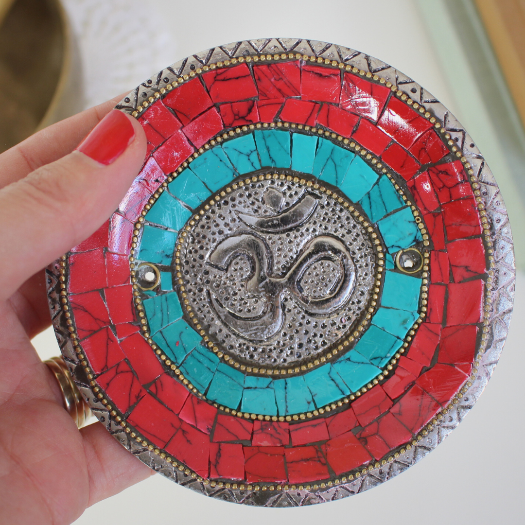 Apportez une énergie spirituelle unique à vos rituels avec ce porte-encens tibétain artisanal orné du symbole sacré Ôm.
Fabriqué à la main en Inde, il associe une mosaïque colorée (rouge, bleu profond, turquoise) et des détails en métal argenté et doré, faisant de chaque pièce une véritable œuvre d’art.