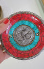 Apportez une énergie spirituelle unique à vos rituels avec ce porte-encens tibétain artisanal orné du symbole sacré Ôm.
Fabriqué à la main en Inde, il associe une mosaïque colorée (rouge, bleu profond, turquoise) et des détails en métal argenté et doré, faisant de chaque pièce une véritable œuvre d’art.