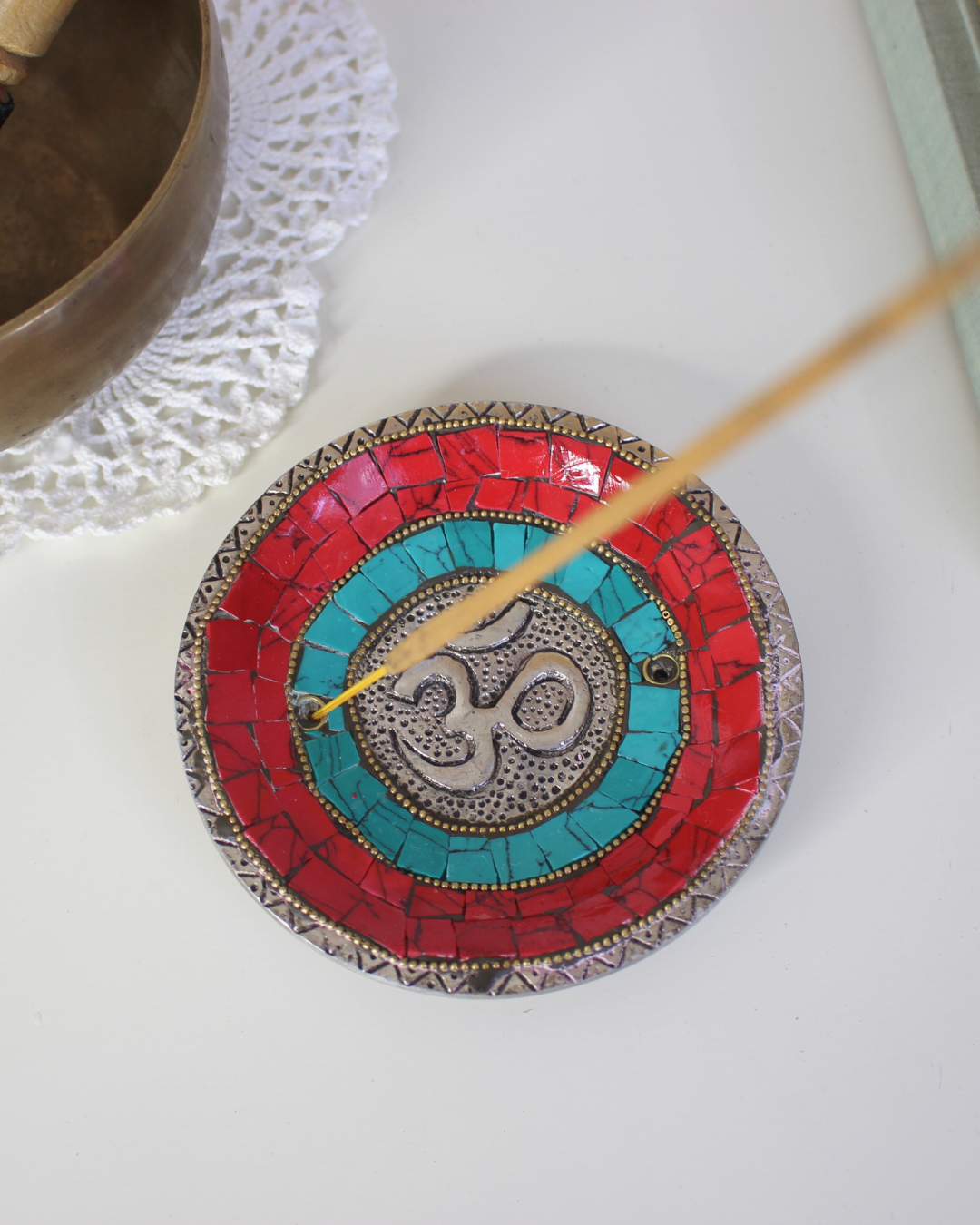 Apportez une énergie spirituelle unique à vos rituels avec ce porte-encens tibétain artisanal orné du symbole sacré Ôm.
Fabriqué à la main en Inde, il associe une mosaïque colorée (rouge, bleu profond, turquoise) et des détails en métal argenté et doré, faisant de chaque pièce une véritable œuvre d’art.