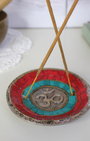 Apportez une énergie spirituelle unique à vos rituels avec ce porte-encens tibétain artisanal orné du symbole sacré Ôm.
Fabriqué à la main en Inde, il associe une mosaïque colorée (rouge, bleu profond, turquoise) et des détails en métal argenté et doré, faisant de chaque pièce une véritable œuvre d’art.