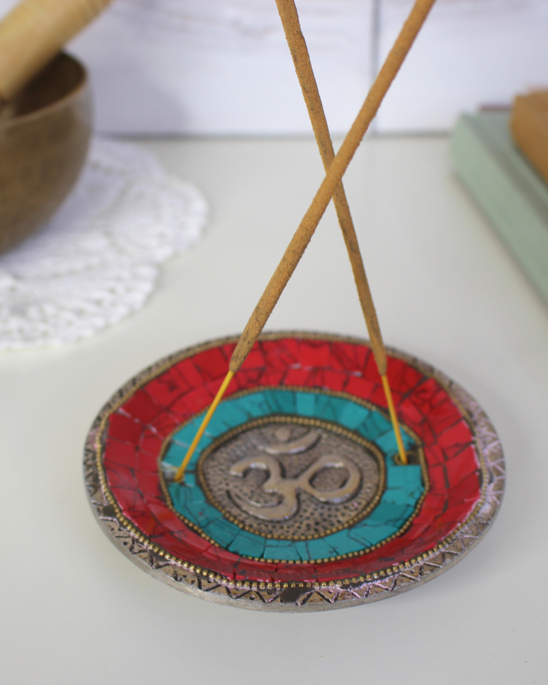Apportez une énergie spirituelle unique à vos rituels avec ce porte-encens tibétain artisanal orné du symbole sacré Ôm.
Fabriqué à la main en Inde, il associe une mosaïque colorée (rouge, bleu profond, turquoise) et des détails en métal argenté et doré, faisant de chaque pièce une véritable œuvre d’art.