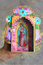 Invitez la spiritualité et la beauté de l’artisanat mexicain dans votre foyer avec cet étui votif artisanal dédié à la Vierge Marie, figure de protection et de lumière universelle.Conçu et peint à la main, cet autel mural coloré est à la fois une œuvre d’art sacrée et un objet de dévotion. Sa vitre ouvrante vous permet d’y déposer vos intentions sur des bouts de papier ou d’exprimer vos prières à Marie, comme le veut la tradition des foyers mayas.