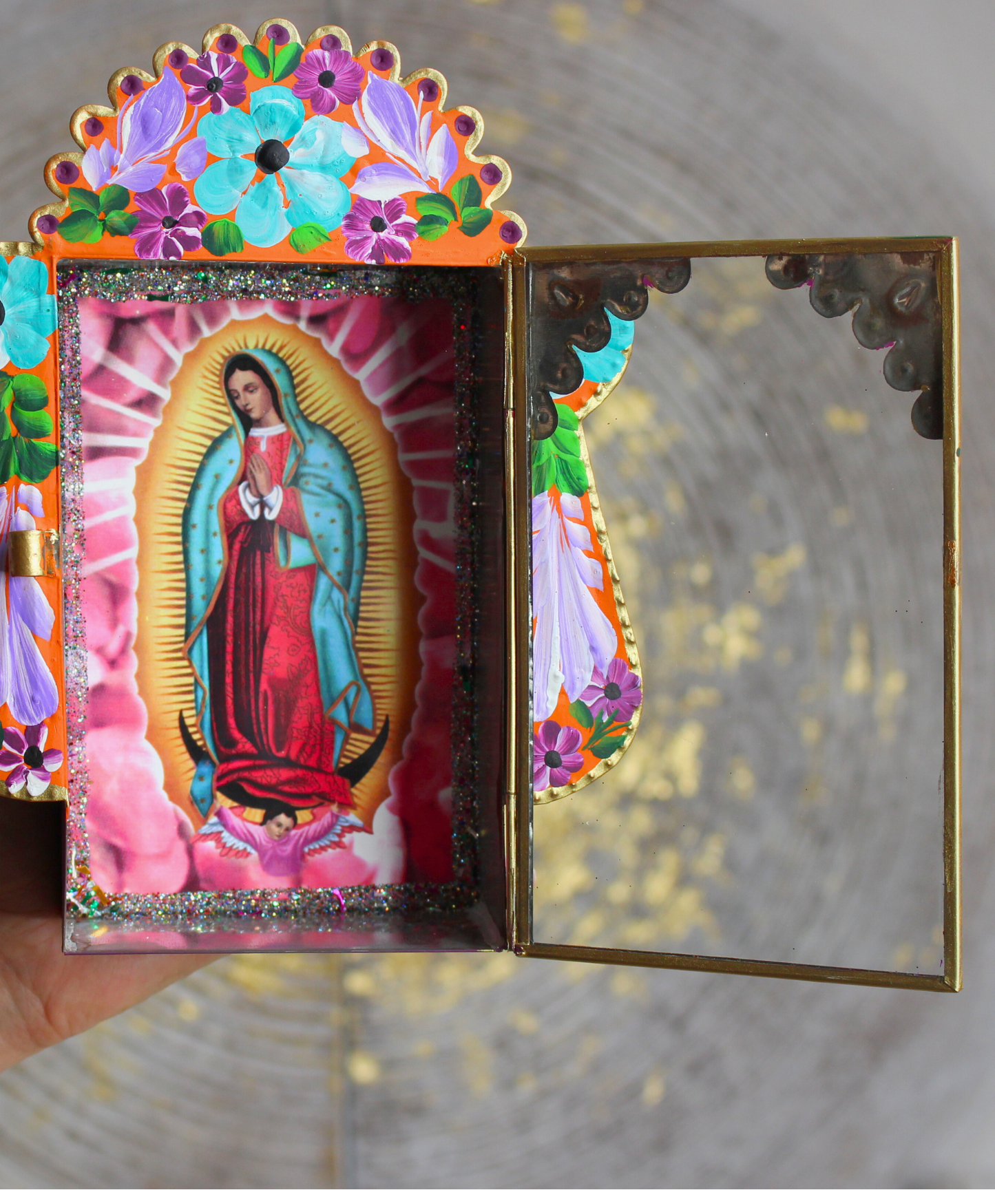 Invitez la spiritualité et la beauté de l’artisanat mexicain dans votre foyer avec cet étui votif artisanal dédié à la Vierge Marie, figure de protection et de lumière universelle.Conçu et peint à la main, cet autel mural coloré est à la fois une œuvre d’art sacrée et un objet de dévotion. Sa vitre ouvrante vous permet d’y déposer vos intentions sur des bouts de papier ou d’exprimer vos prières à Marie, comme le veut la tradition des foyers mayas.